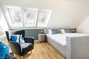 Ein modernes Schlafzimmer mit einer Schlafgalerie, einer Schlafcouch, einem Sessel und einem kleinen Beistelltisch.