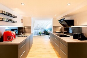 A modern kitchen with a central island, built-in appliances, and a view into a dining area. - Holiday apartment with 1 bedroom (Ahlbeck (Seebad))