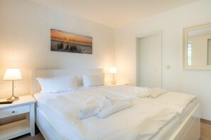 Ein Hotelzimmer mit einem Bett, zwei Nachttischlampen, einem Bild an der Wand und einer Tür.