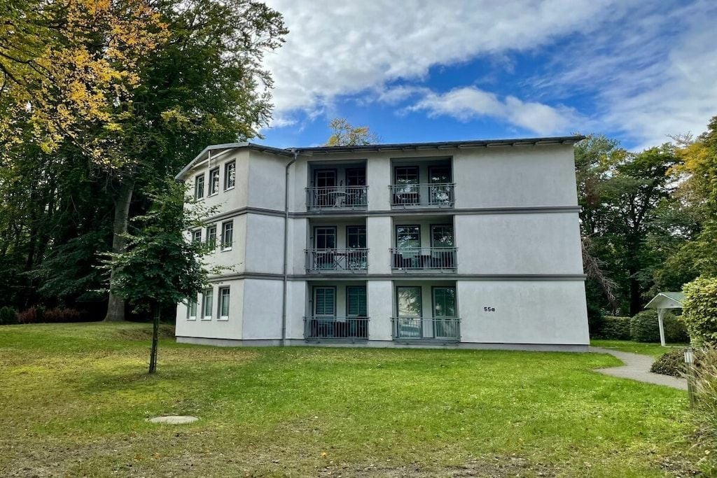 A multi-story building with a flat roof, large windows, and a balcony on the second floor.