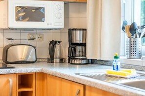 Eine Küche mit Mikrowelle, Toaster, Kaffeemaschine und Geschirr auf der Arbeitsfläche.