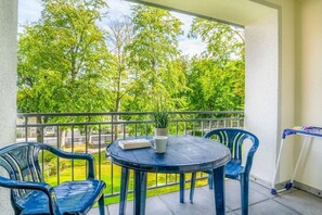 A balcony with a round table, two chairs, a potted plant, and a small table with items. - House at Buchenpark 11 (Heringsdorf (Seebad))