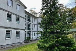 A multi-story building with a symmetrical facade, large windows, and a well-maintained lawn. - House at Buchenpark 11 (Heringsdorf (Seebad))