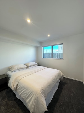 A bedroom with a large bed, a window with a view, and a ceiling light.