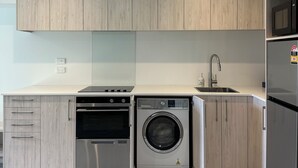 Una cuina moderna amb electrodomèstics integrats, com ara una rentadora, forn i microones.