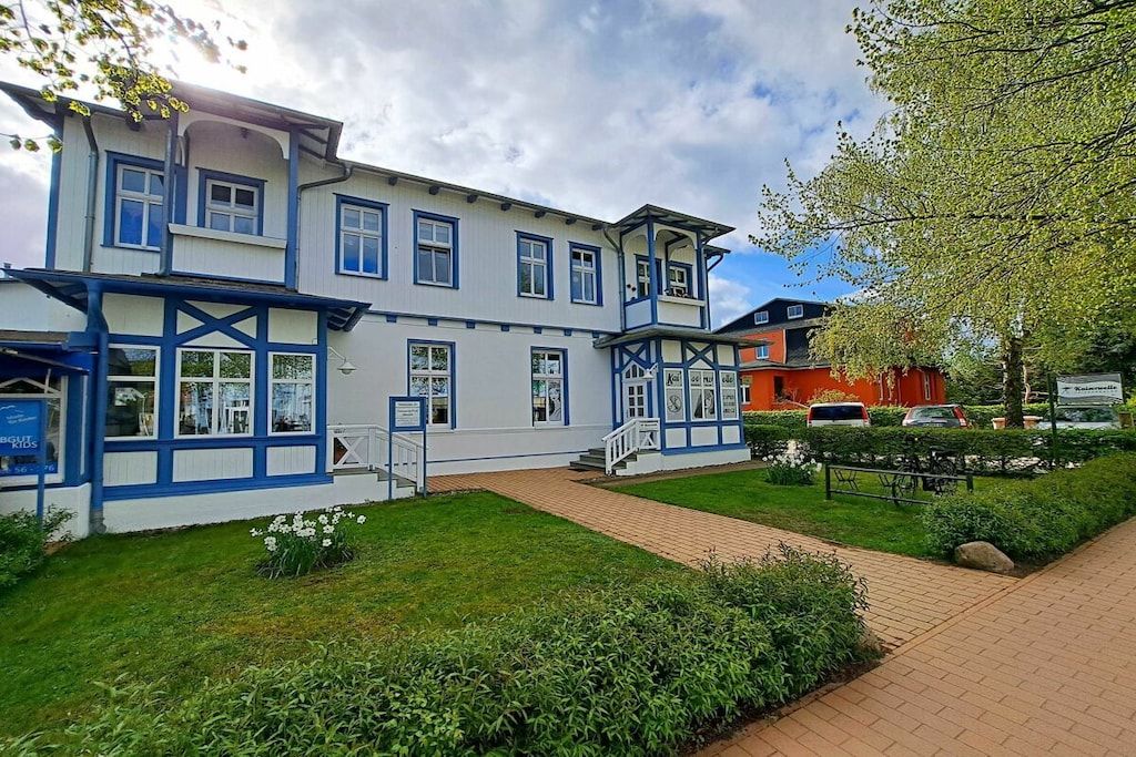 A two-story building with a balcony, a brick pathway, and a well-maintained garden.