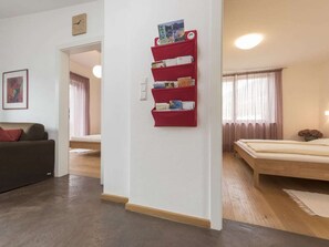 A room with a bed, a sofa, a red bookshelf, and a door leading to another room. - "red" on the Sandwiesen Farm (Gargazzone)