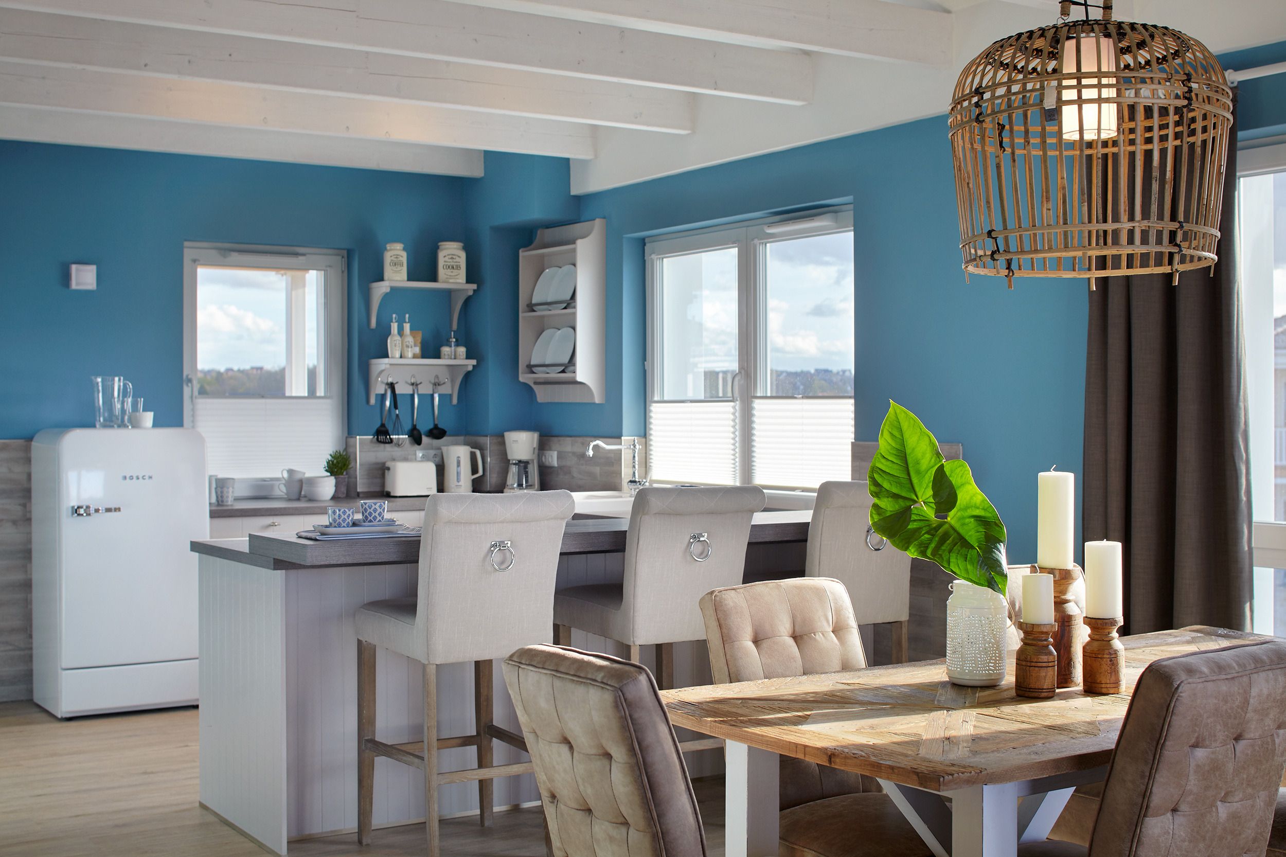 Una cocina moderna con electrodomésticos blancos, una isla de madera y un comedor con mesa y sillas.