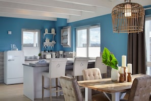 A modern kitchen with white appliances, a wooden island, and a dining area with a table and chairs. - Vrbo Property (Heiligenhafen)