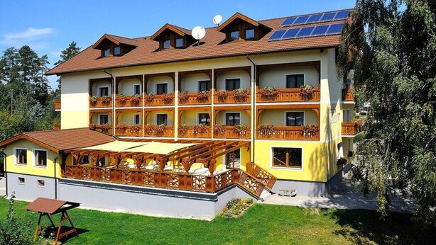 Un hotel de varios pisos con balcones, un área de estar exterior techada y paneles solares en el techo.