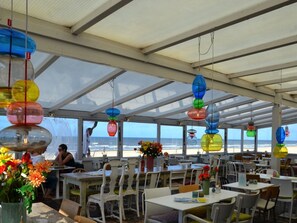 An outdoor dining area with tables and chairs, large windows, and hanging decorative lights. - Holiday Home in Bergen With Swimming Pool (Bergen)