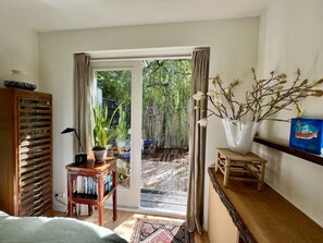 A room with a bed, a wooden cabinet, a small table with a plant, a vase with branches, and a painting on the wall. - Holiday Home in Bergen With Swimming Pool (Bergen)