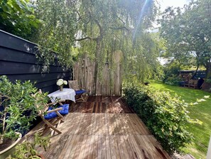 A wooden deck with a table and chairs, surrounded by greenery and a wooden fence. - Holiday Home in Bergen With Swimming Pool (Bergen)