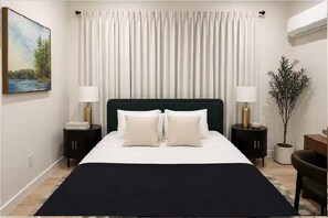 A bedroom with a bed, two bedside tables, a nightstand, a potted plant, and a painting on the wall. - King Bed-Unbeatable Location-Bishop Arts- Unit 3 (Dallas)