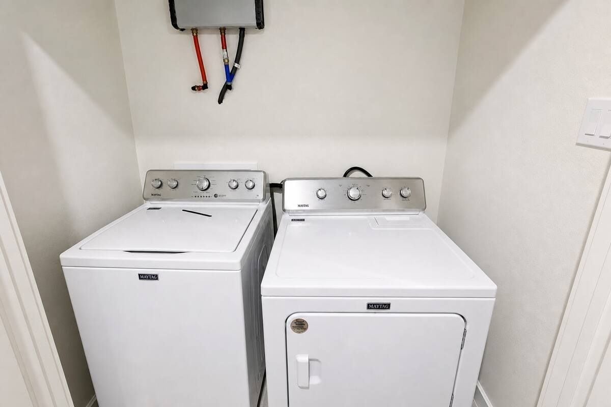 A laundry room with two Maytag washing machines and a utility wall with electrical outlets.