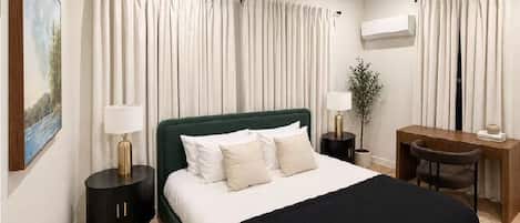 Une chambre d’hôtel avec un lit, des tables de chevet, un bureau et une chaise.