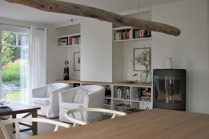 Ein modernes Wohnzimmer mit weißen Möbeln, einem Kamin und Bücherregalen.