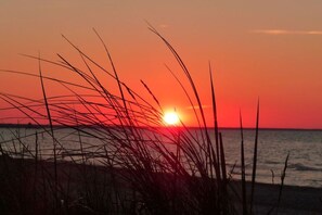 A sunset over the ocean with grass in the foreground. - Holiday rooms with 0 bedrooms (Kölpinsee)