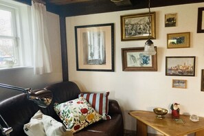 A room with a brown leather sofa, a wooden side table, and a wall adorned with framed pictures. - Holiday home in Born with swimming pool (Born)