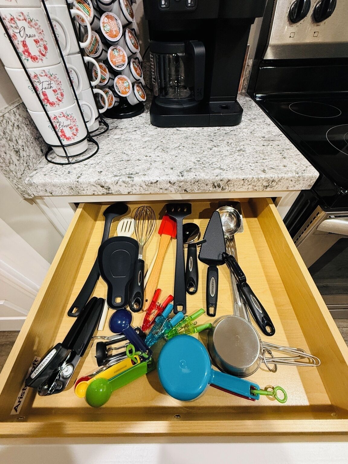 Un cajón de cocina con varios utensilios y artículos de cocina.
