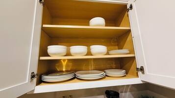 A kitchen cabinet with multiple shelves holding white bowls and plates.