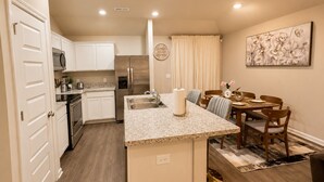 A modern kitchen with white cabinets, stainless steel appliances, and a granite countertop. - Modern Luxury 3BR Home in Cullman (Cullman)