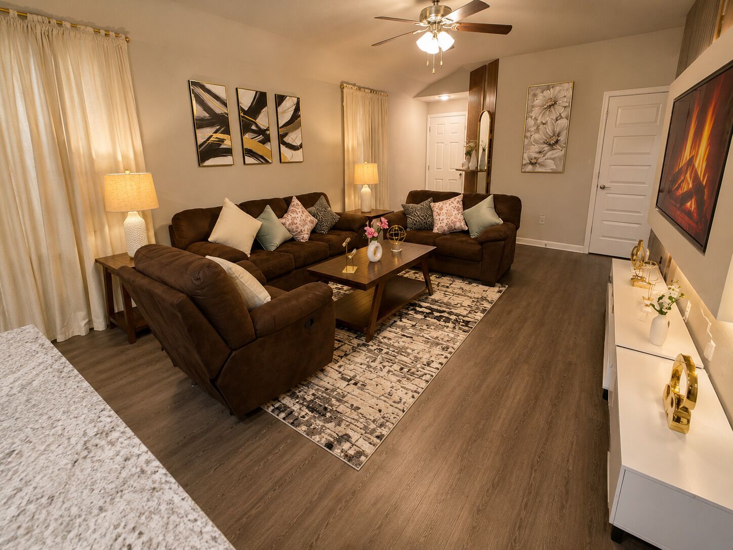 A living room with a brown sofa set, a coffee table, and a ceiling fan.