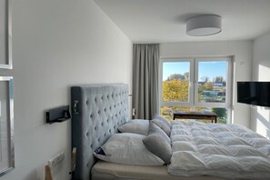 A bedroom with a bed, a television, and a window with a view of trees. - Holiday apartment with 1 bedroom (Kühlungsborn)