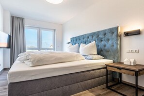 Een moderne hotelkamer met een groot bed, een nachtkastje en een raam met uitzicht.
