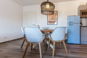 Un coin repas avec une table et des chaises, un luminaire suspendu et un réfrigérateur bleu.