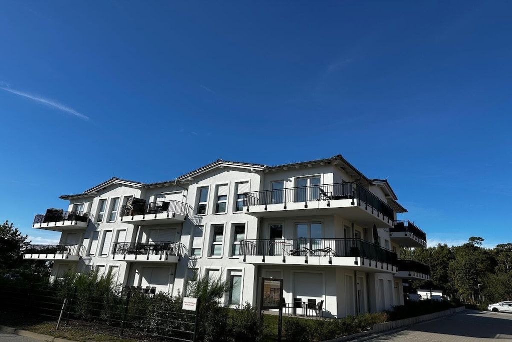 Un immeuble résidentiel à plusieurs étages, doté de balcons, d’une entrée sécurisée et surplombant un ciel dégagé.