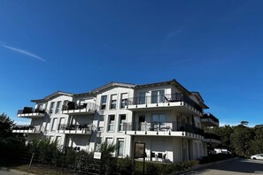 A multi-story residential building with balconies, a gated entrance, and a clear sky. - Holiday apartment with 1 bedroom (Kühlungsborn)