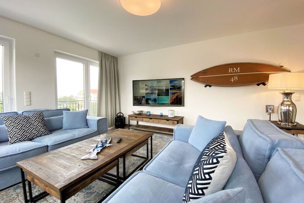 Una sala de estar moderna con un sofá, una mesa de centro y un televisor montado en la pared.