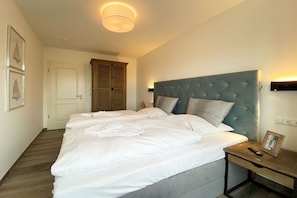 Ein Schlafzimmer mit einem großen Bett, einem Nachttisch, einer Wandlampe und einem Beistelltisch.