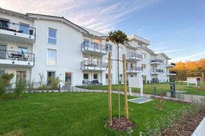 A multi-story residential building with balconies, a well-maintained lawn, and a clear sky. - Holiday apartment with 1 bedroom (Kühlungsborn)
