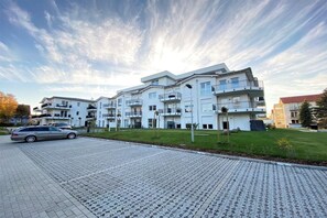 Un immeuble résidentiel à plusieurs étages, doté de balcons et d’une allée pavée.