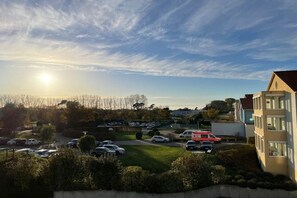 A residential area with parked cars, a building with a sloped roof, and a clear sky. - Holiday apartment with 1 bedroom (Kühlungsborn)