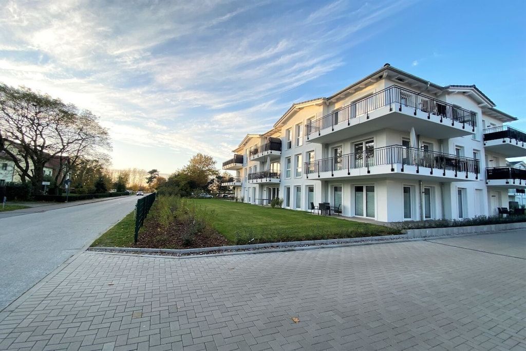 Ein mehrstöckiges Wohngebäude mit Balkonen, einer gepflasterten Auffahrt und einem gepflegten Rasen.