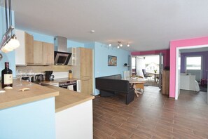 A modern kitchen with a dining area, wooden cabinets, and a visible wine bottle. - Holiday apartment in Glowe with swimming pool (Glowe)