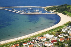 Luchtbeeld van een kustgebied met een jachthaven, strand en woongebouwen.
