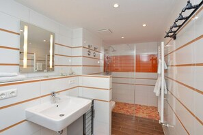 Een badkamer met een wastafel, spiegel en douchehoek.