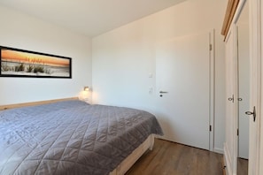 Ein Schlafzimmer mit einem Bett, einer Tür und einer Wandleuchte.