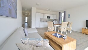 Ett modernt vardagsrum med en soffa, ett soffbord i trä och en matplats med stolar.