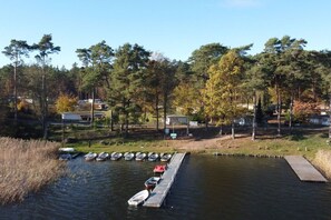 A lakeside dock with several boats, surrounded by trees and a small building. - im Ferienpark Seenland GmbH (Lychen)