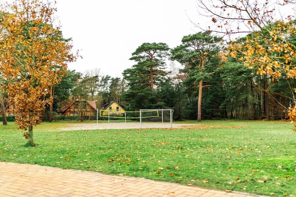 Ein Sportplatz mit einem Tor, umgeben von Bäumen und einem Gebäude im Hintergrund.