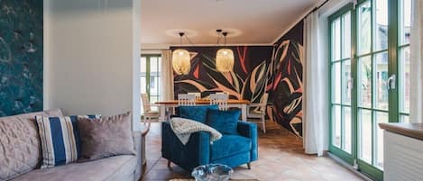 Una sala de estar con un sofá, un sillón azul, una mesa de centro y un mural en la pared.