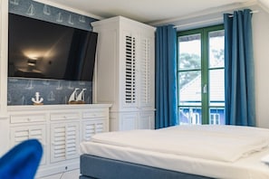 A bedroom with a bed, a wardrobe, and a window with curtains. - Holiday home in Glowe with swimming pool (Glowe)