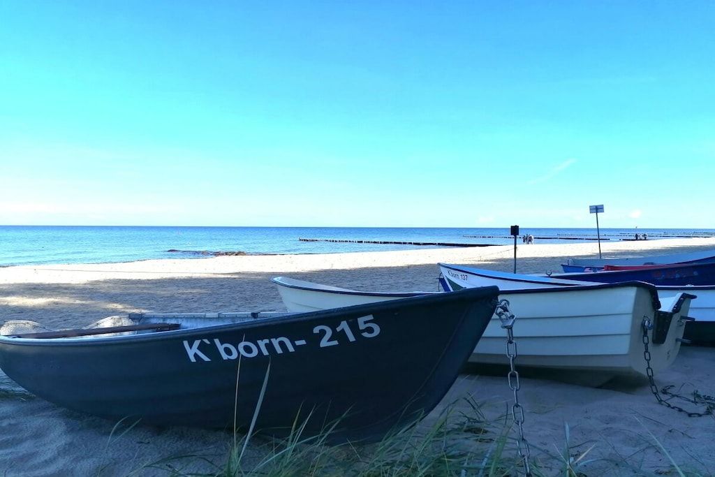 Une plage avec plusieurs bateaux amarrés à un poteau, un ciel dégagé et une mer calme.