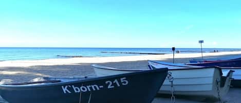 A beach with several boats tied to a post, a clear sky, and a calm sea.