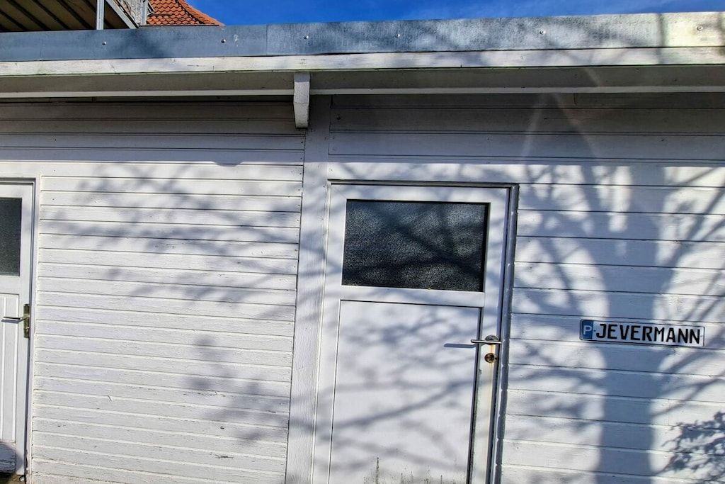 Een gebouw met een garage deur en een raam waarop de tekst 'JEVERMANN' staat.